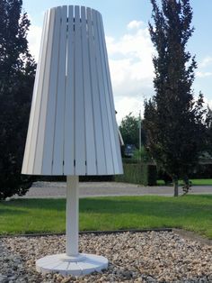 a white lamp sitting on top of a gravel field