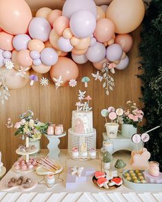 an assortment of desserts on a table with balloons in the air and flowers hanging from the ceiling