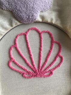 a close up of a embroidery on a pillow with a pink object in the background