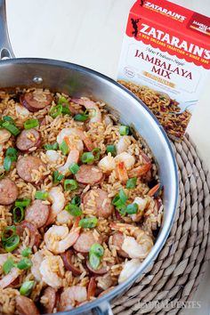 a pan filled with shrimp and rice next to a carton of zaatan's