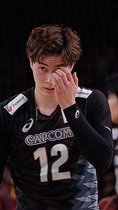 a young man holding his hand to his face while standing in front of a crowd