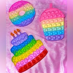 two cakes made out of legos on a pink blanket with one cake shaped like a rainbow and the other as a cupcake