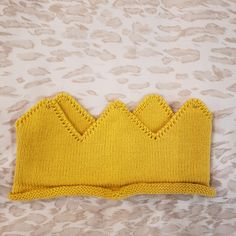 a yellow knitted headband with scalloped edges on a leopard print background