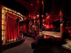 a dimly lit room with red curtains and lights on the walls, couches and tables