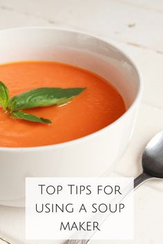 a white bowl filled with carrot soup and garnished with green leaves on top