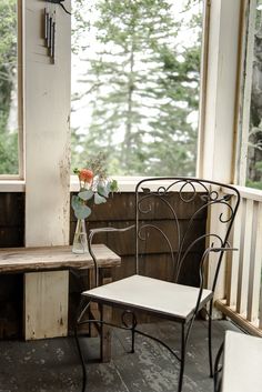 a chair sitting on top of a porch next to a wooden table and window sill