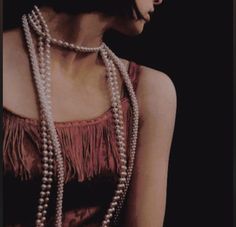 a woman in a brown dress with pearls on her necklace