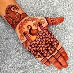 henna tattoo on the palm of someone's hand with peacocks and flowers