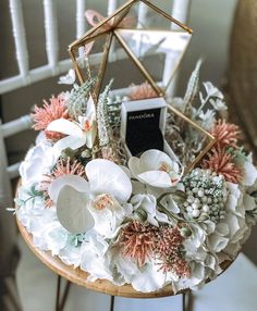 an arrangement of flowers and succulents is displayed on a small round table