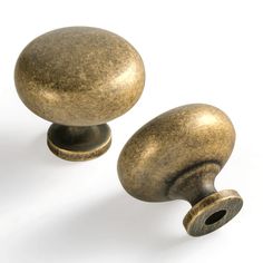 two brass colored knobs on a white background