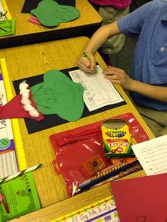 a young boy sitting at a desk working on his paper cutout character creation project