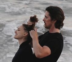 a man and woman standing next to each other on the beach