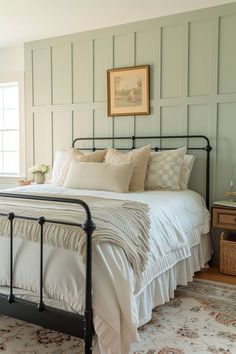 a bed with white linens and pillows in a bedroom next to a painting on the wall