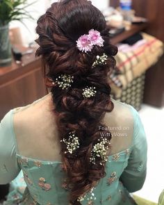 the back of a woman's head with long hair and flowers in her hair