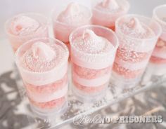 there are many pink desserts in small cups on the tray together, and one is filled with powdered sugar