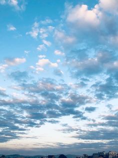 an airplane is flying high in the sky above some buildings and trees on a cloudy day