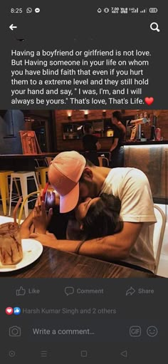 two people sitting at a table with food in front of them and one person kissing the other