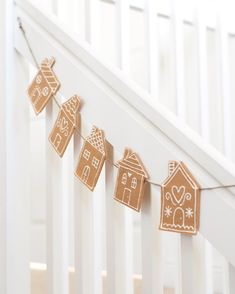 gingerbread cut out houses are hung on a string from the bannister railing