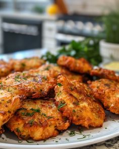 some fried food on a white plate with parsley sprinkled around it and lemon wedges in the background