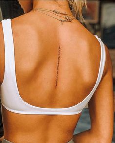 the back of a woman's white top with a tattoo on her left shoulder