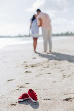 a pair of red shoes sitting on top of a sandy beach