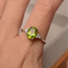 This halo ring features a 7*9mm oval cut real peridot and sterling silver finished with rhodium. Customization is available. It is made by hand, and it will take about 7 days to finish the ring after your payment is completed. Main stone: natural peridot (August birthstone) Peridot weight: Approx 2.25 ct Metal type: sterling silver / 14k gold Accent stone: cz Customization is available, I also can make it with 14k solid gold (white or yellow or rose) and diamond accent stone, just feel free to c Peridot Ring Engagement, Peridot Engagement Rings, August Birthstone Ring, Green Gemstone Ring, Future Engagement Rings, Peridot Jewelry, Art Deco Wedding Rings, Wedding Anniversary Rings, Peridot Stone