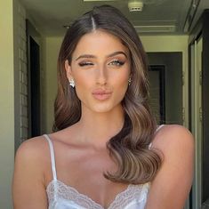 a woman with long brown hair wearing a white bra and earrings is posing for the camera