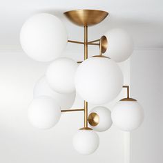 a modern chandelier with white balls hanging from it's brass finish fixture