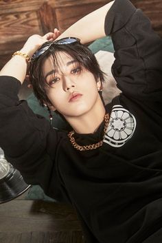 a person laying on top of a bed wearing a black shirt and chain around his neck