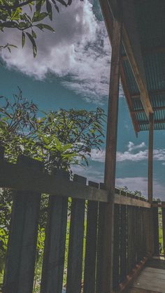 a wooden walkway leading to a covered area with trees and bushes on the other side