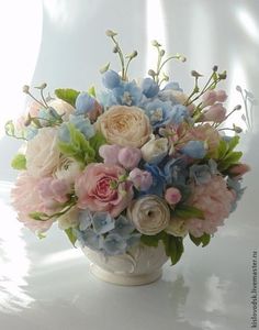 a vase filled with lots of flowers on top of a white tablecloth covered floor