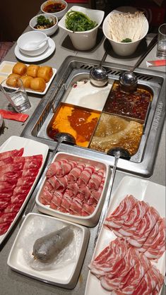 an assortment of meats and vegetables are displayed on the counter in front of other dishes