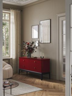 a living room scene with focus on the dresser and flowers in the vase, along with two windows