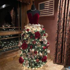 a mannequin is decorated with red and white flowers, silver ornaments and lights