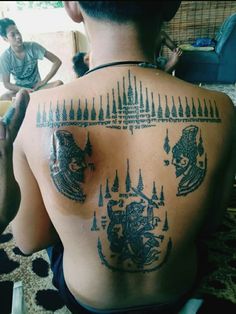 the back of a man with tattoos on his upper and lower back, which is decorated with images of animals