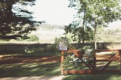 a wooden gate with flowers on it in the grass