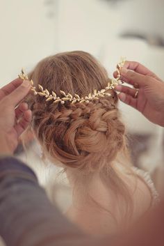 a woman is braiding her hair with a gold chain headpiece on top of her head