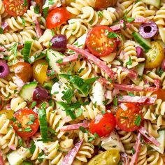 a pasta salad with tomatoes, cucumbers, olives, and parsley