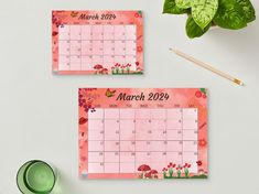 two pink calendars with flowers on them next to a green cup and plant in the background