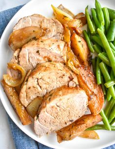 a white plate topped with meat, green beans and potatoes on top of a blue cloth