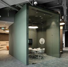 an office meeting room with glass partitions and round tables in the center, surrounded by concrete flooring