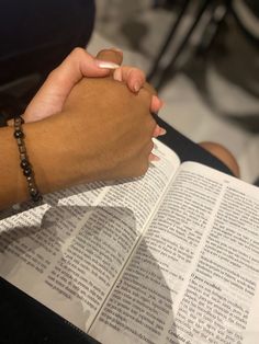 two people holding hands over an open book