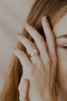 a woman holding her hand up to her face with a diamond ring on her finger