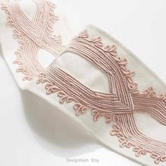 a white and pink ribbon with an intricate design on the side, sitting on top of a table