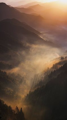 the sun shines through the foggy mountains in the distance, as seen from above