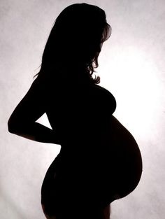 the silhouette of a pregnant woman with her hands on her hips, against a white background