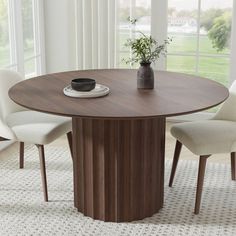 a round table with four chairs around it and a vase filled with flowers on top