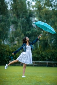 a woman in a white dress holding an umbrella and jumping into the air with her legs spread wide