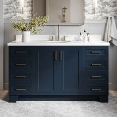 a bathroom with blue cabinets and white counter tops, two mirrors on the wall above it