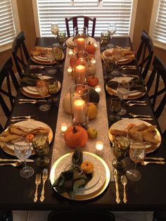 a dining room table is set with candles and plates